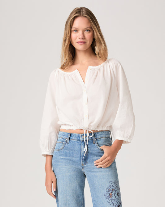 Women wearing a white blouse paired with light wash jeans against a white background.