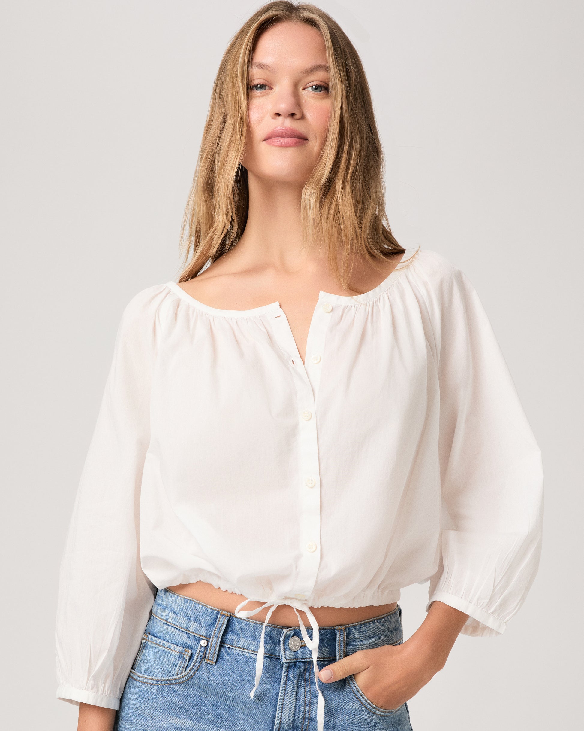 Women wearing a white blouse paired with light wash jeans against a white background.