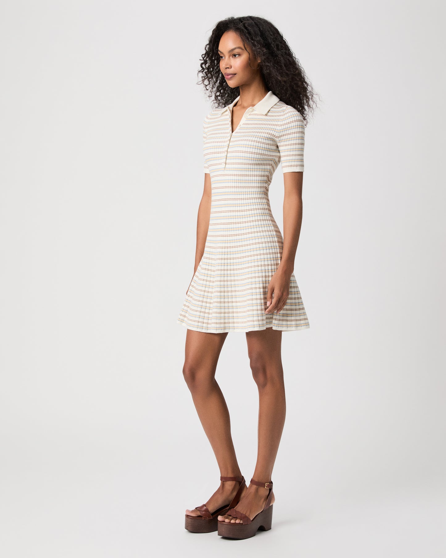 women wearing a mini white stripped dress with brown heels against a white background 