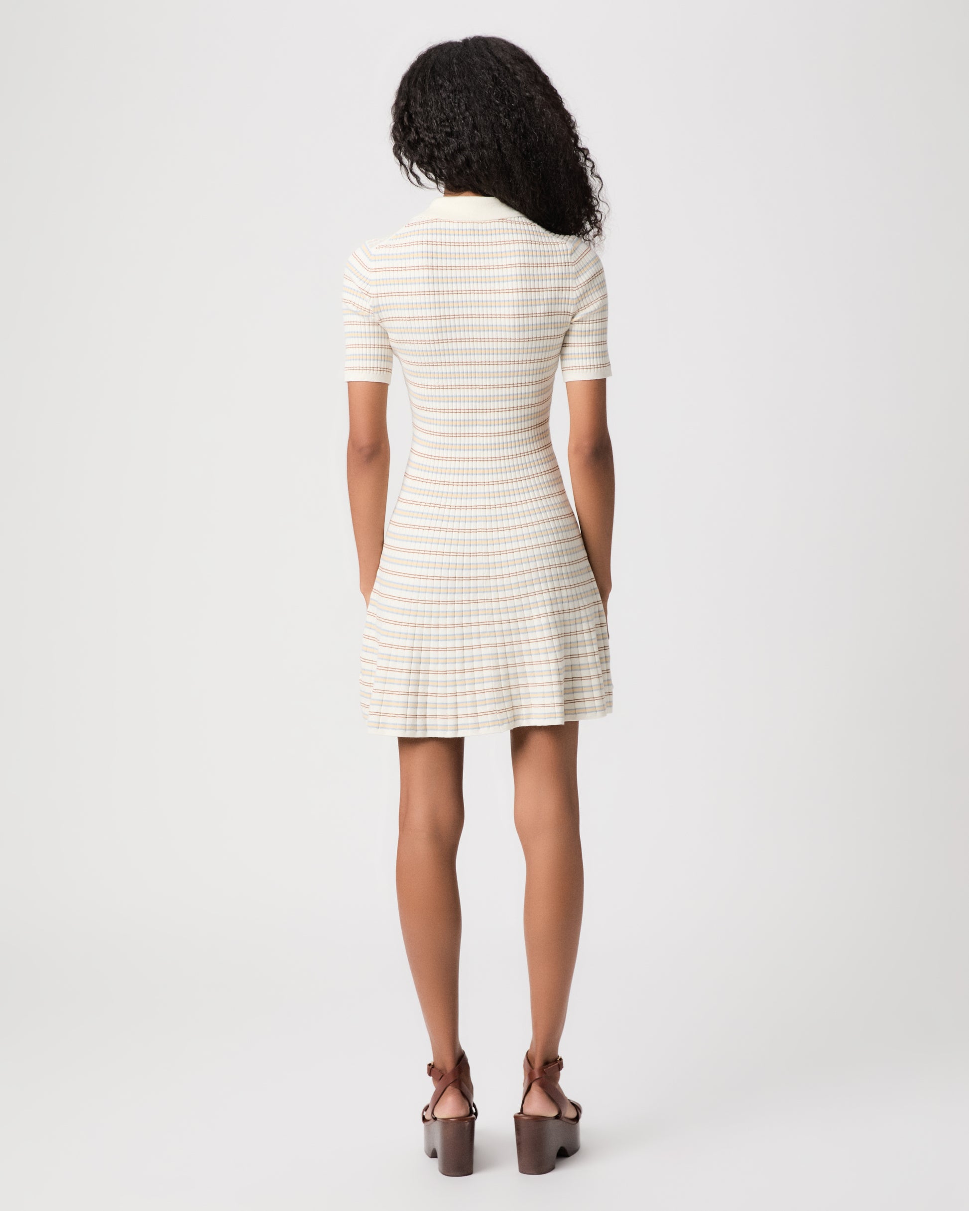 women wearing a mini white stripped dress with brown heels against a white background 