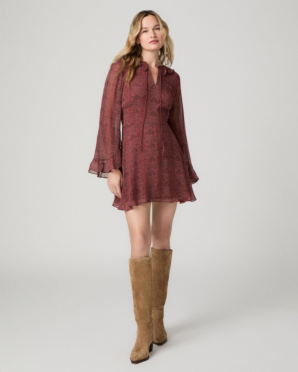 Full-length front view of a woman wearing the garnet floral-print Elspeth Dress with tan suede boots.