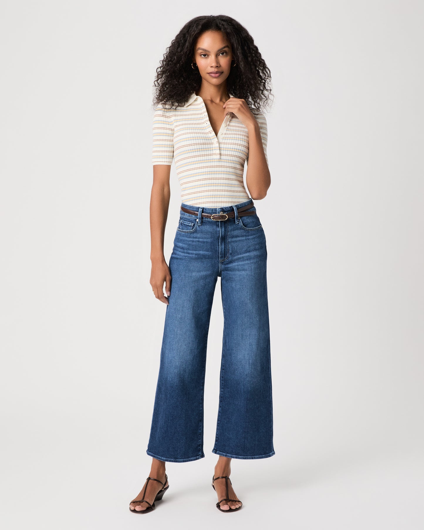 women wearing a white stripped top paired with blue jeans and black sandals against a white background 