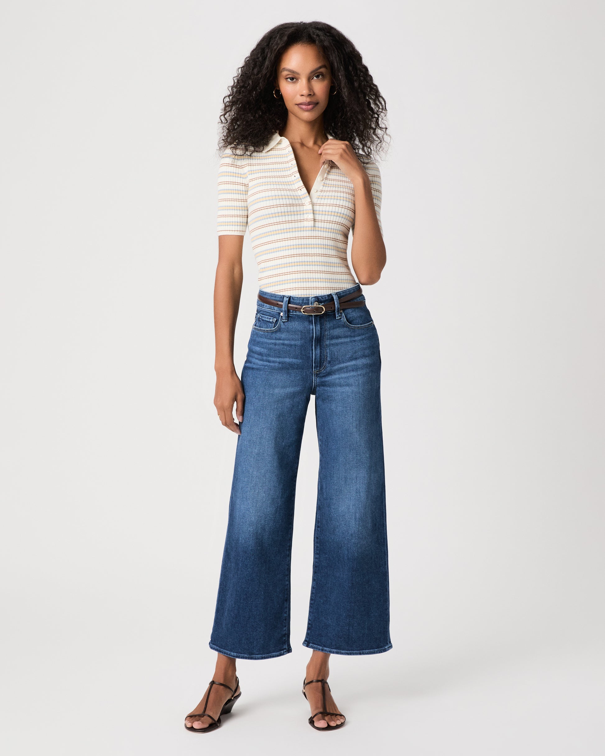women wearing a white stripped top paired with blue jeans and black sandals against a white background 