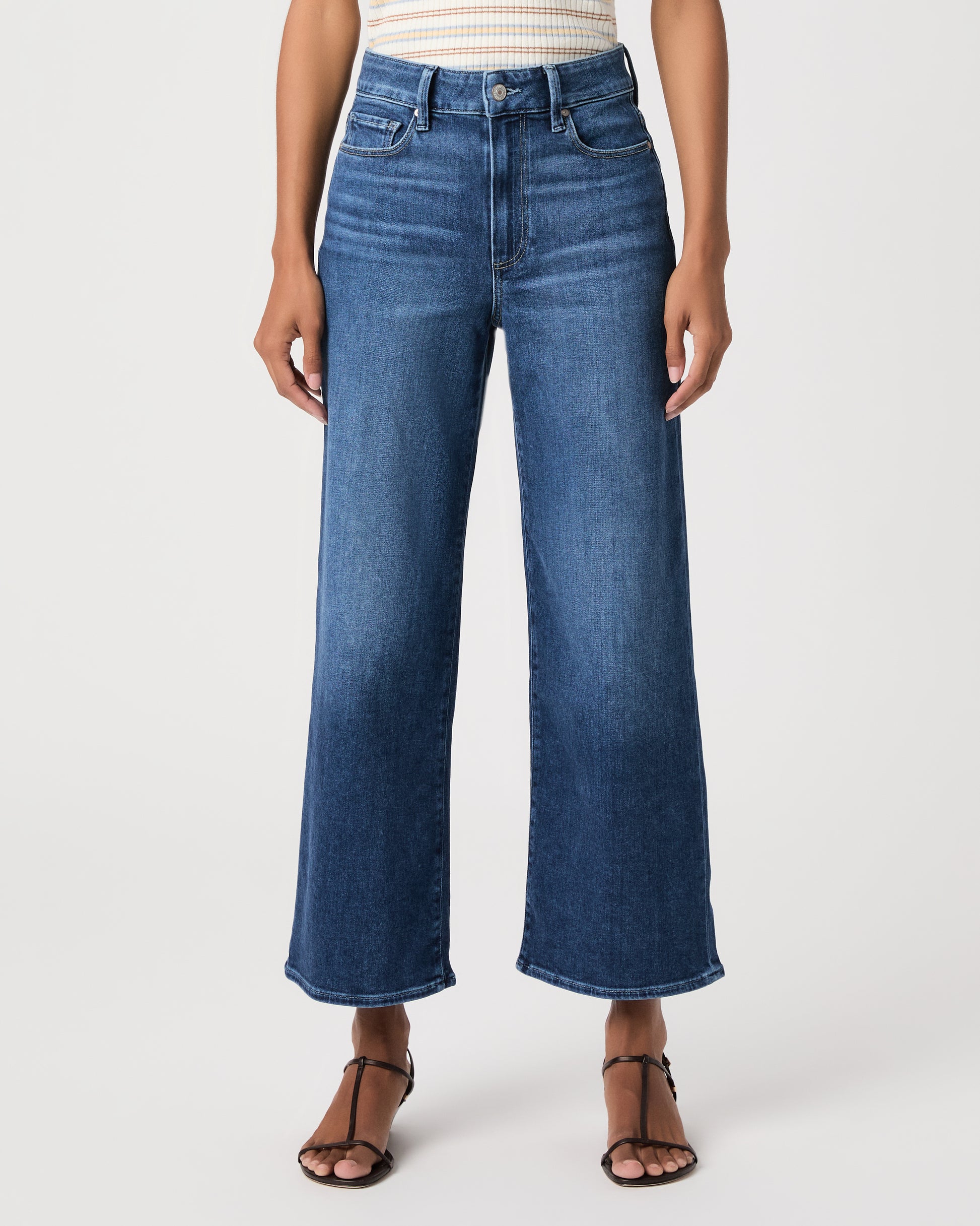 women wearing a white stripped top paired with blue jeans and black sandals against a white background 