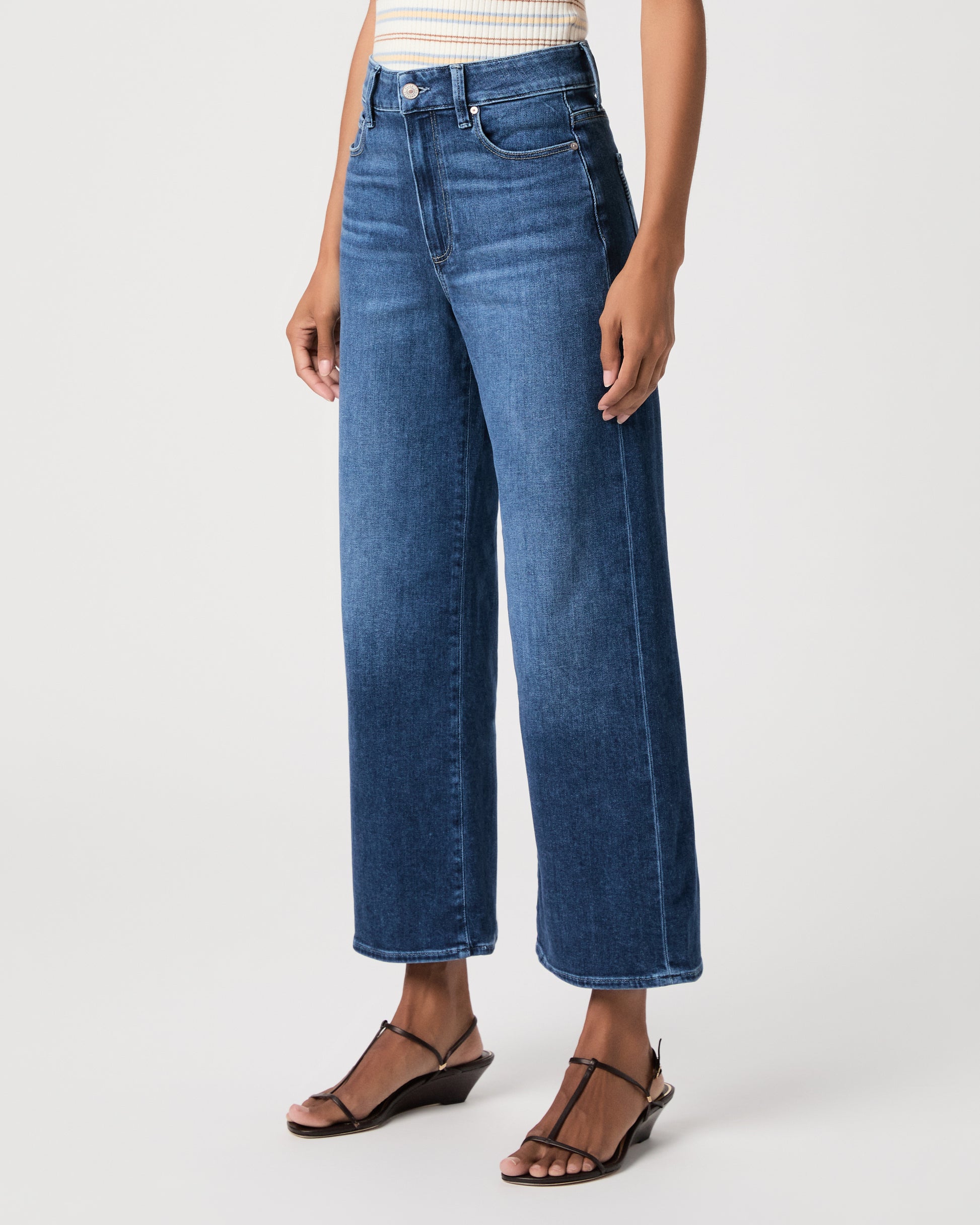 women wearing a white stripped top paired with blue jeans and black sandals against a white background 
