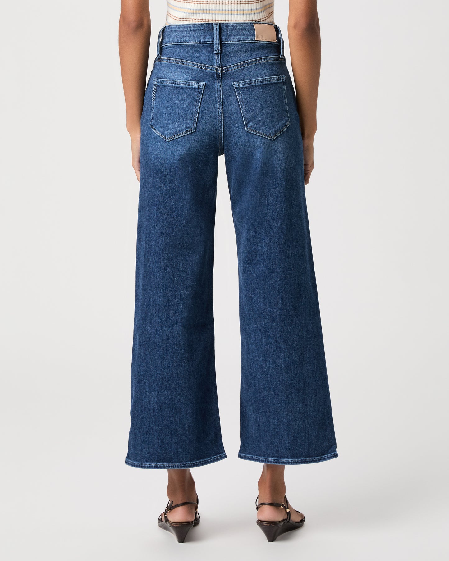 women wearing a white stripped top paired with blue jeans and black sandals against a white background 