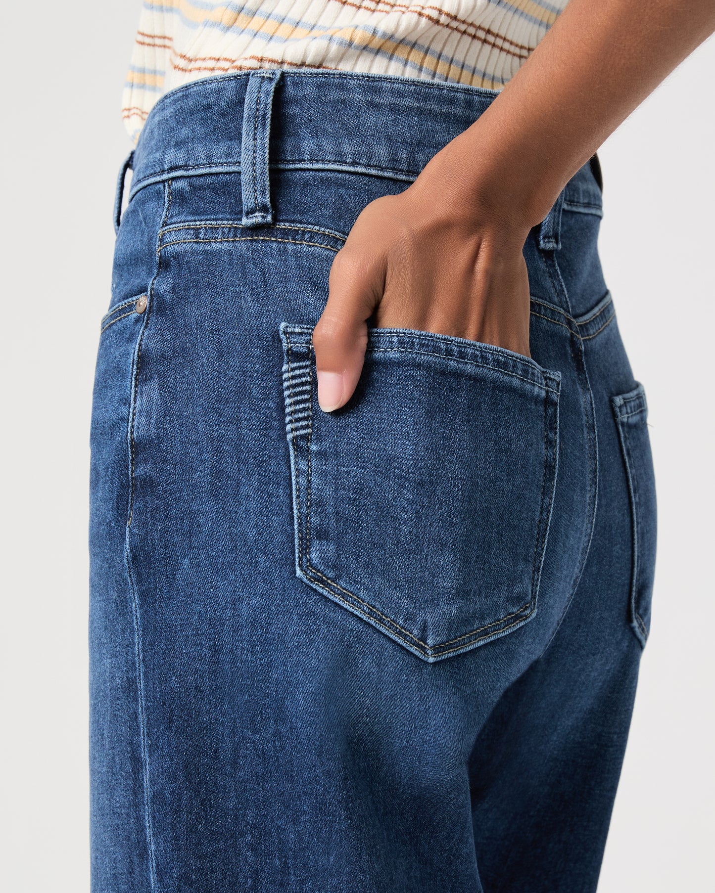 women wearing a white stripped top paired with blue jeans and black sandals against a white background 