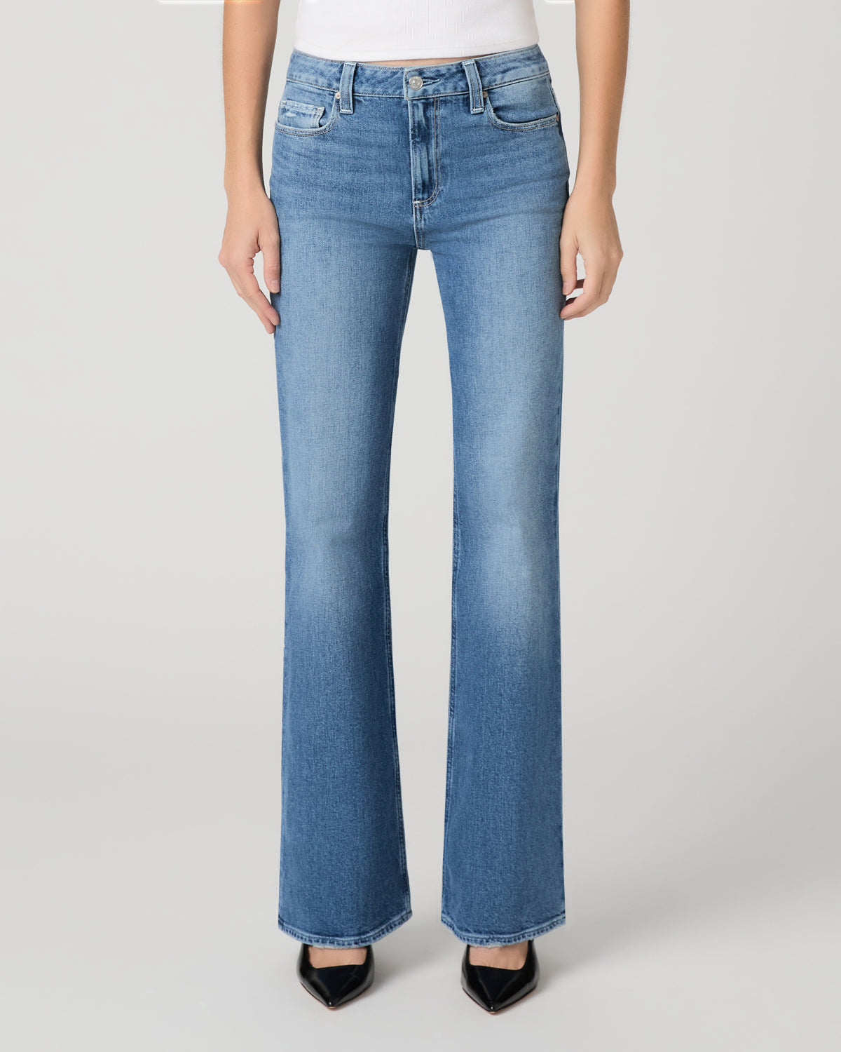 Women wearing a white top paired with blue jean and black heels against a white background