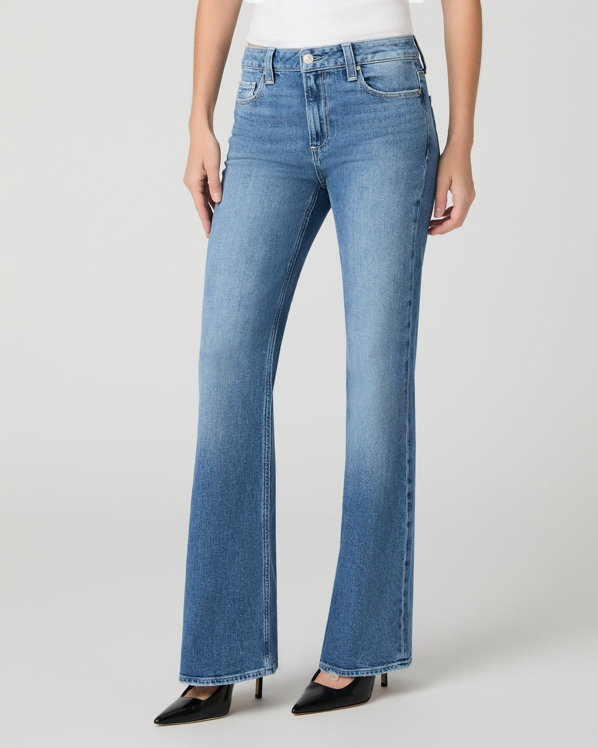 Women wearing a white top paired with blue jean and black heels against a white background