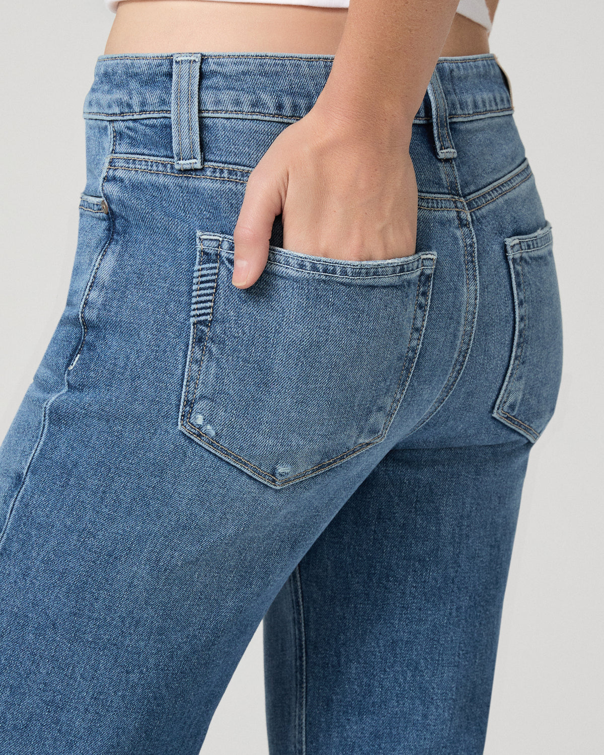 Women wearing a white top paired with blue jean and black heels against a white background