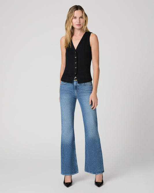 Women wearing a black vest top paired with blue jean and black heels against a white background