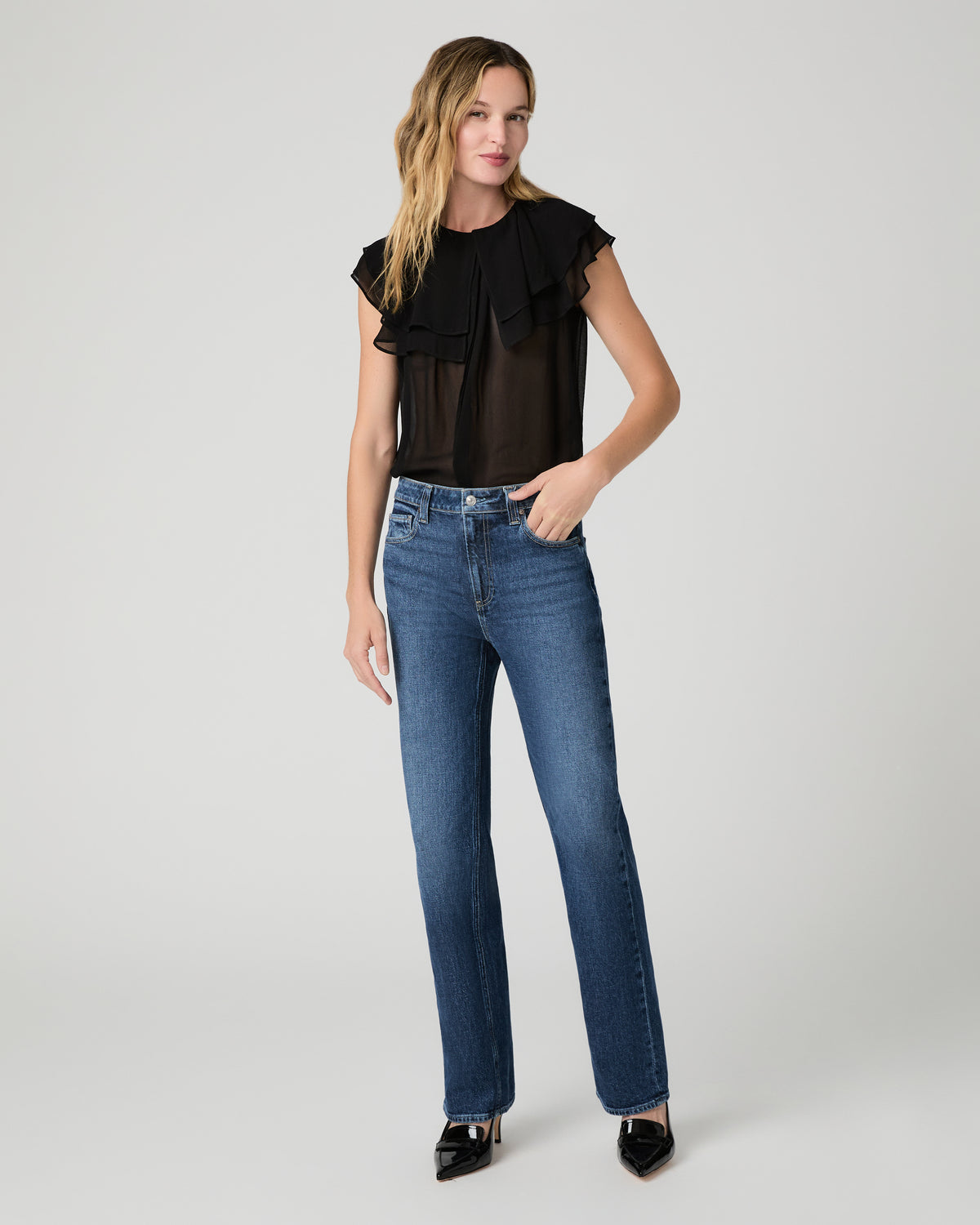 Women wearing a black top paired with blue jean and black heels against a white background