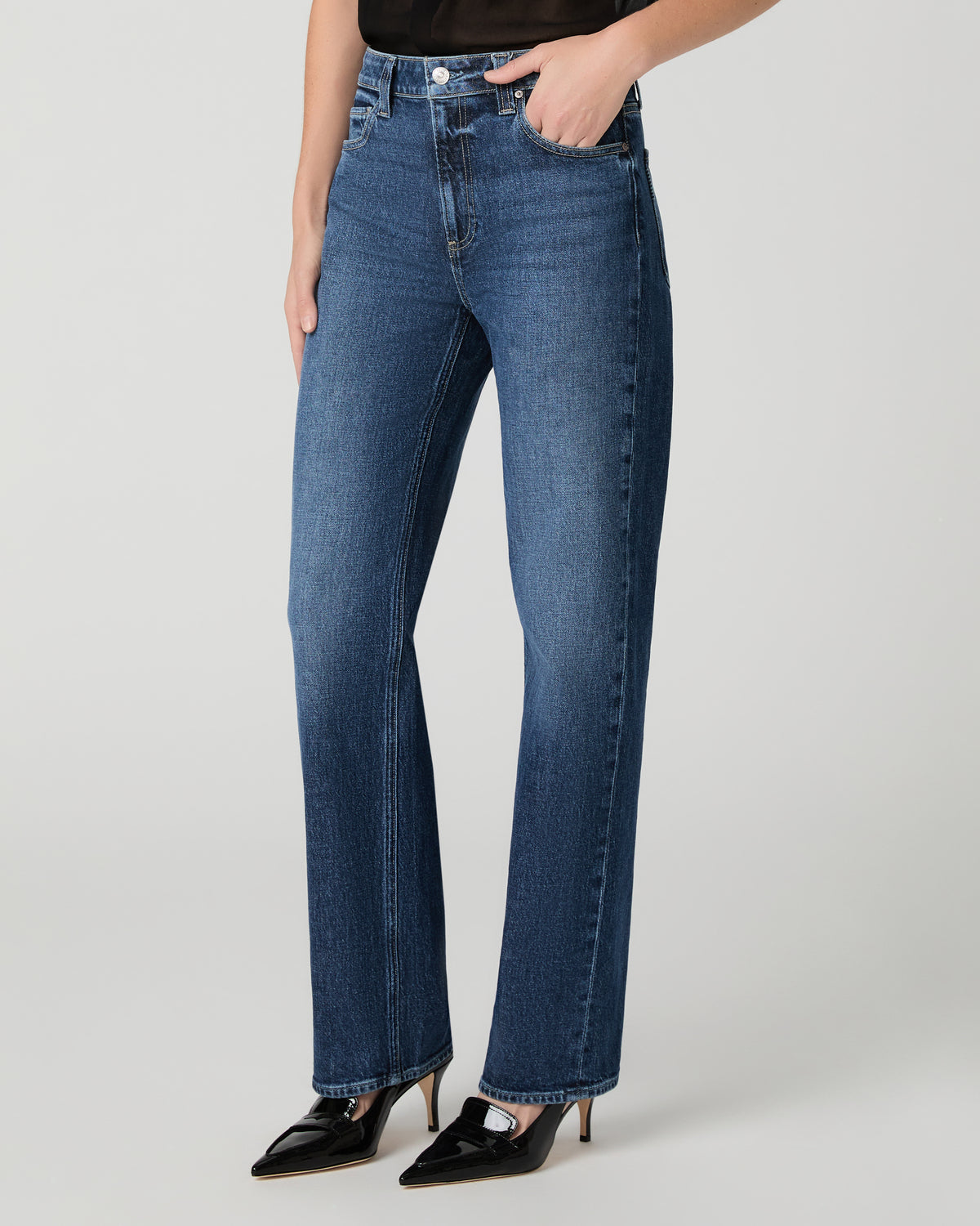 Women wearing a black top paired with blue jean and black heels against a white background