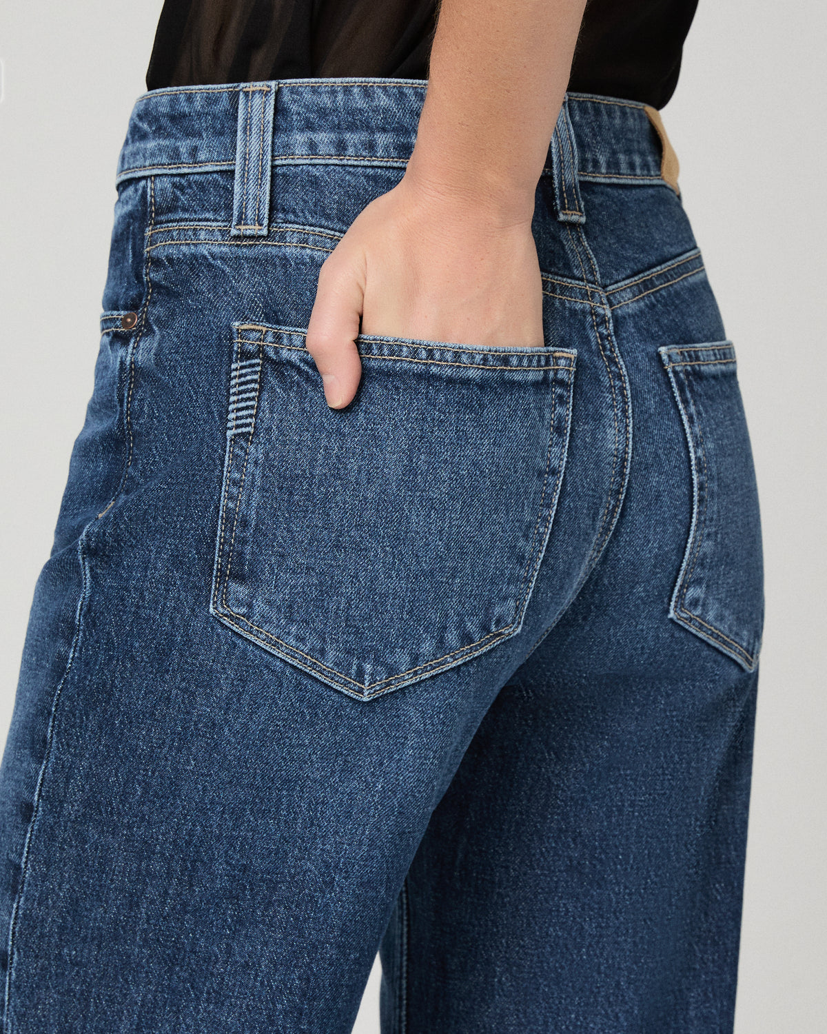 Women wearing a black top paired with blue jean and black heels against a white background