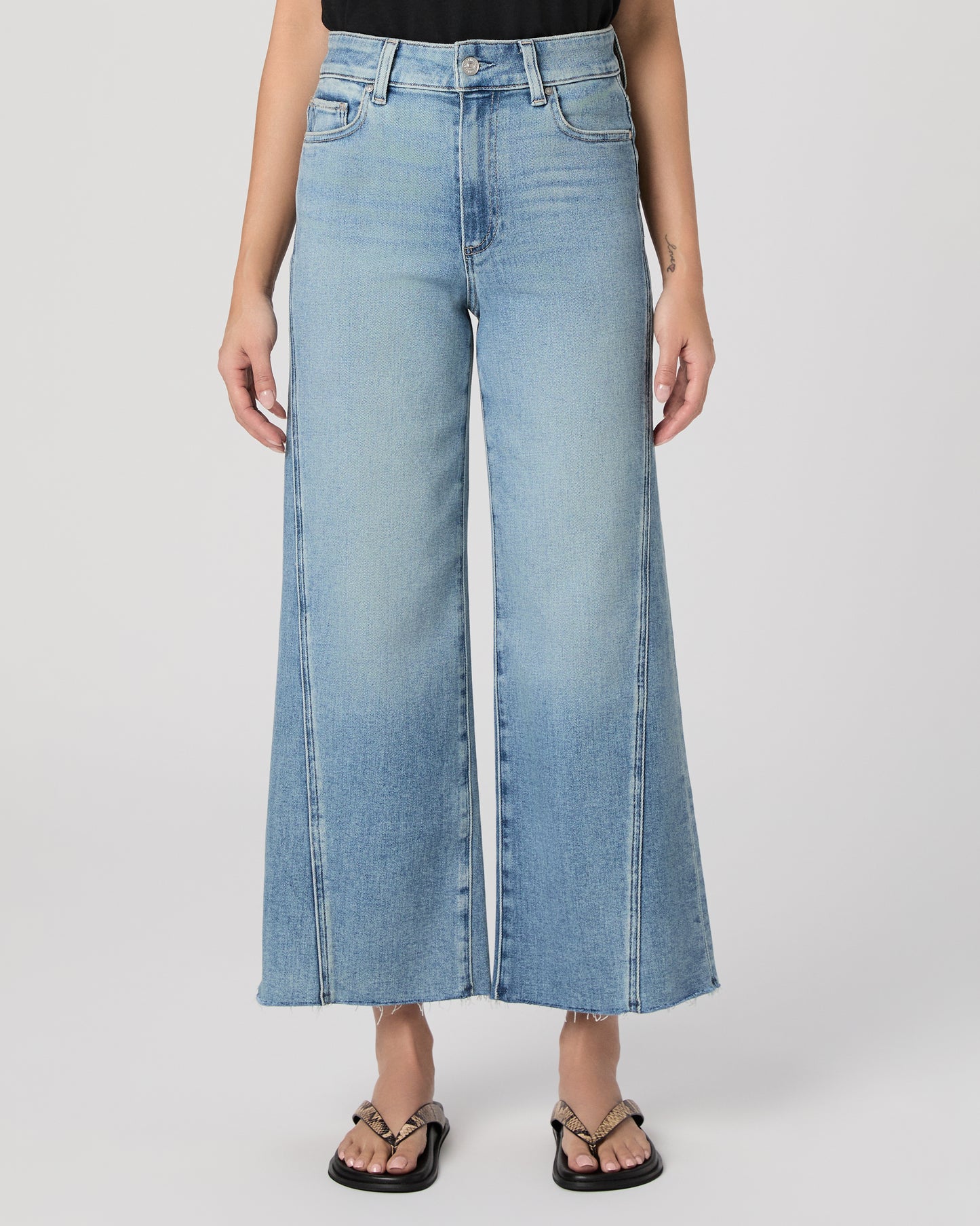 Woman wearing a black top and blue jeans on a white background