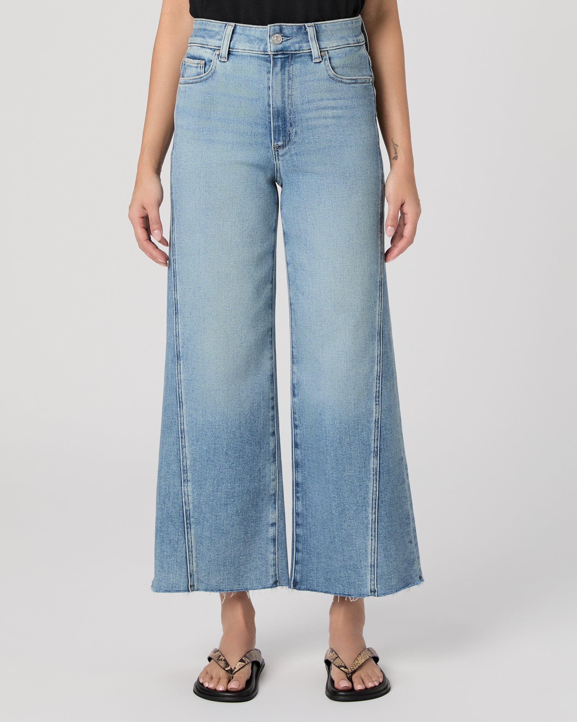 Woman wearing a black top and blue jeans on a white background