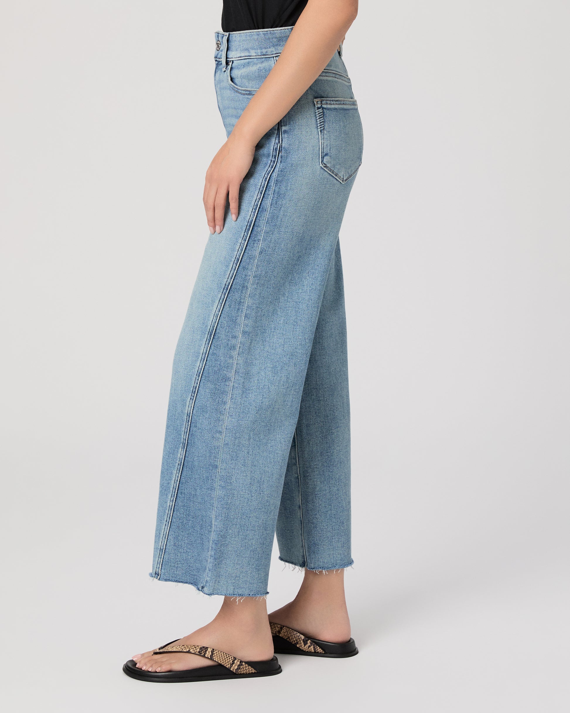 Woman wearing a black top and blue jeans on a white background