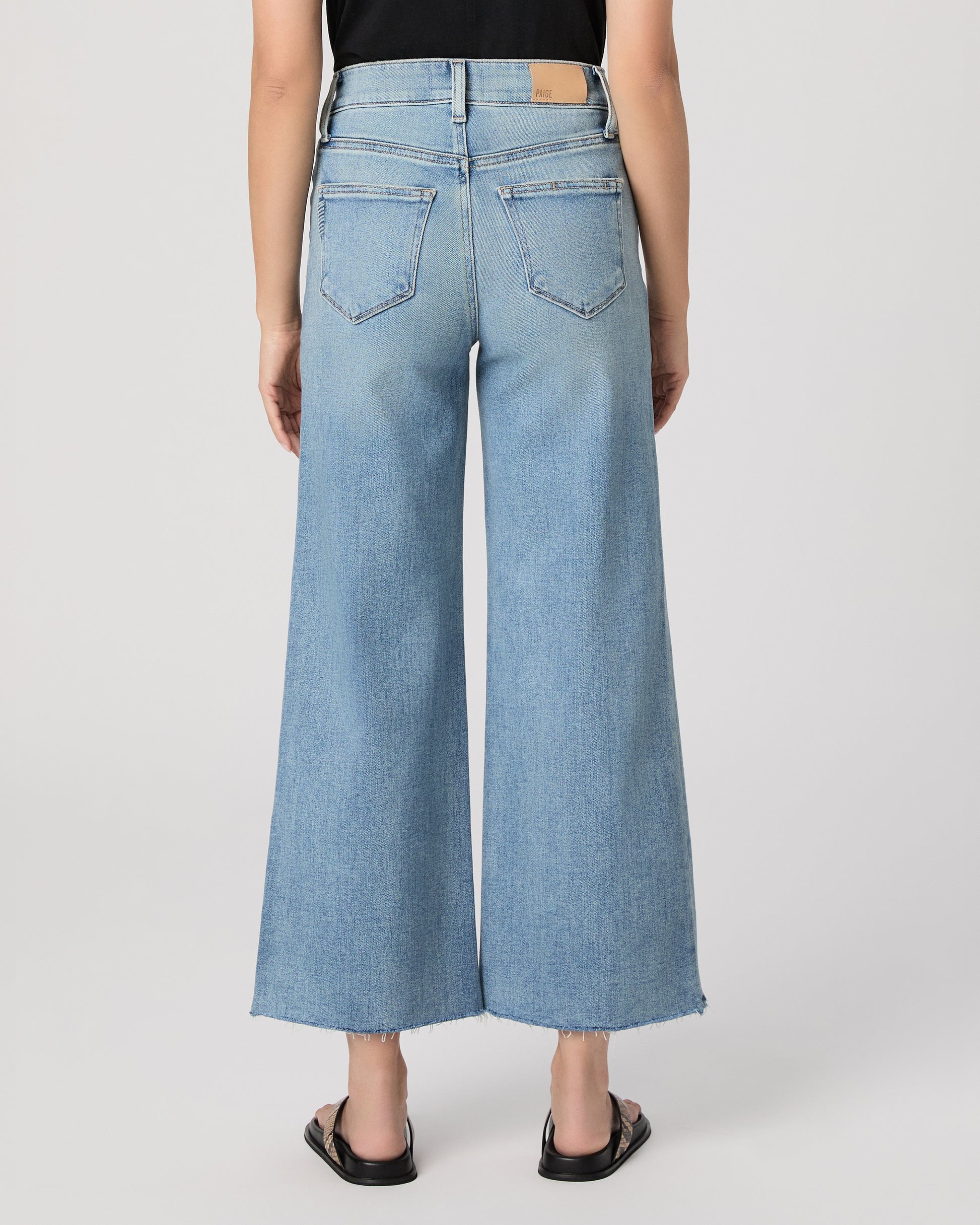 Woman wearing a black top and blue jeans on a white background