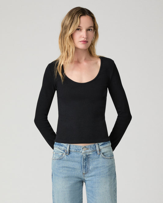 Women wearing a black long sleeve top paired with blue jeans against a white background