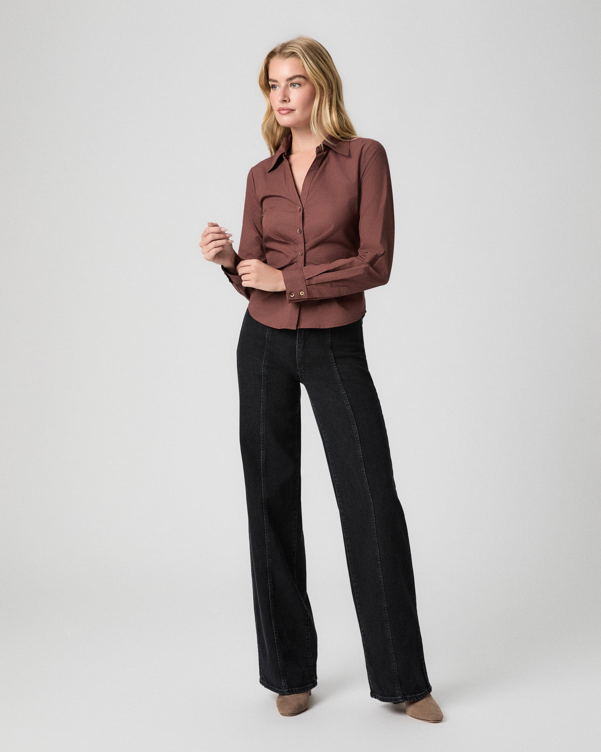 Sasha Wide Leg Jean in Downtown Noir black; model stands with one hand at her hip, in a fitted brown button-up shirt and tan pointed heels