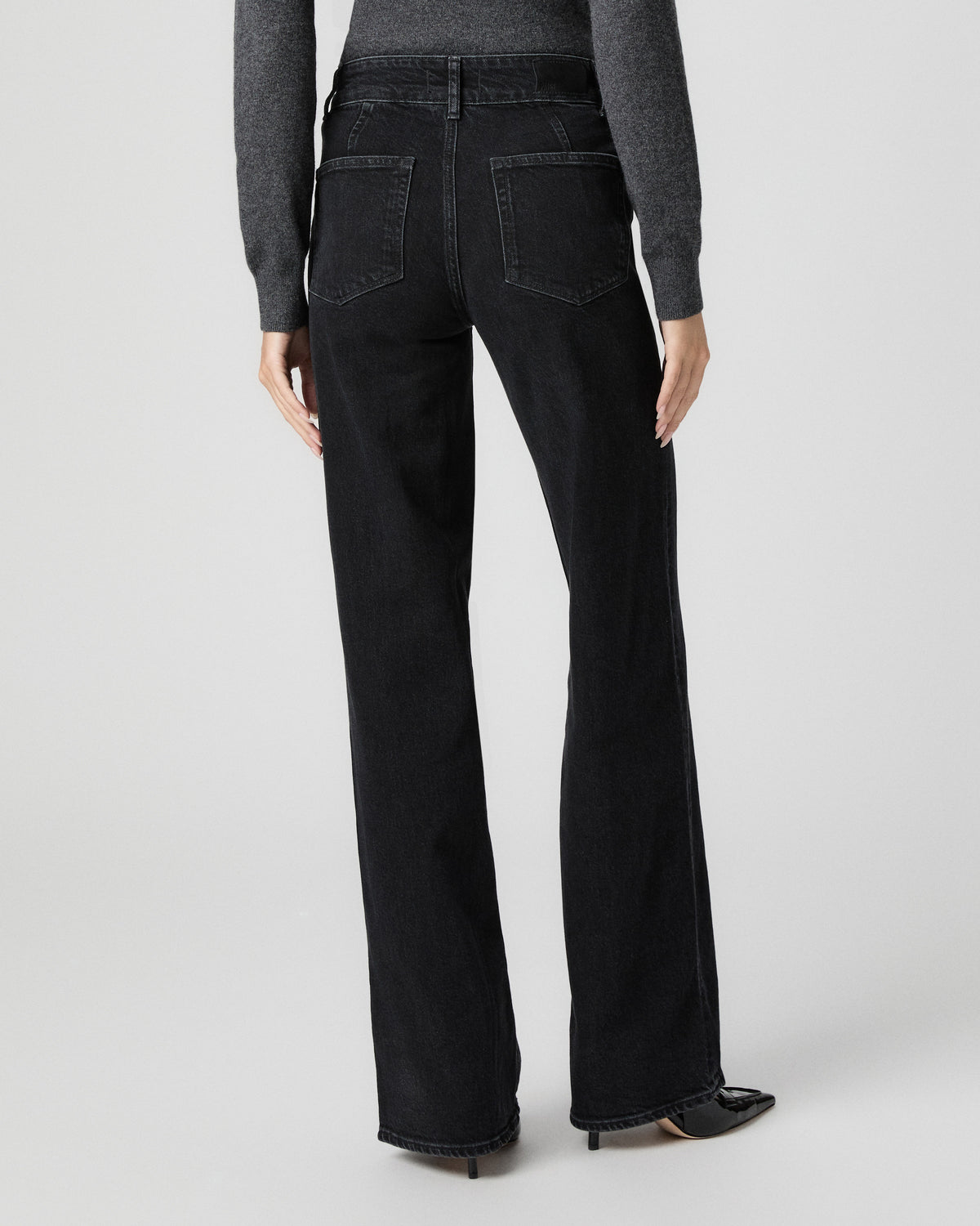 Back view from the waist down of the Sasha Wide Leg Jean in Downtown Noir black, worn with a grey top and black pointed heels