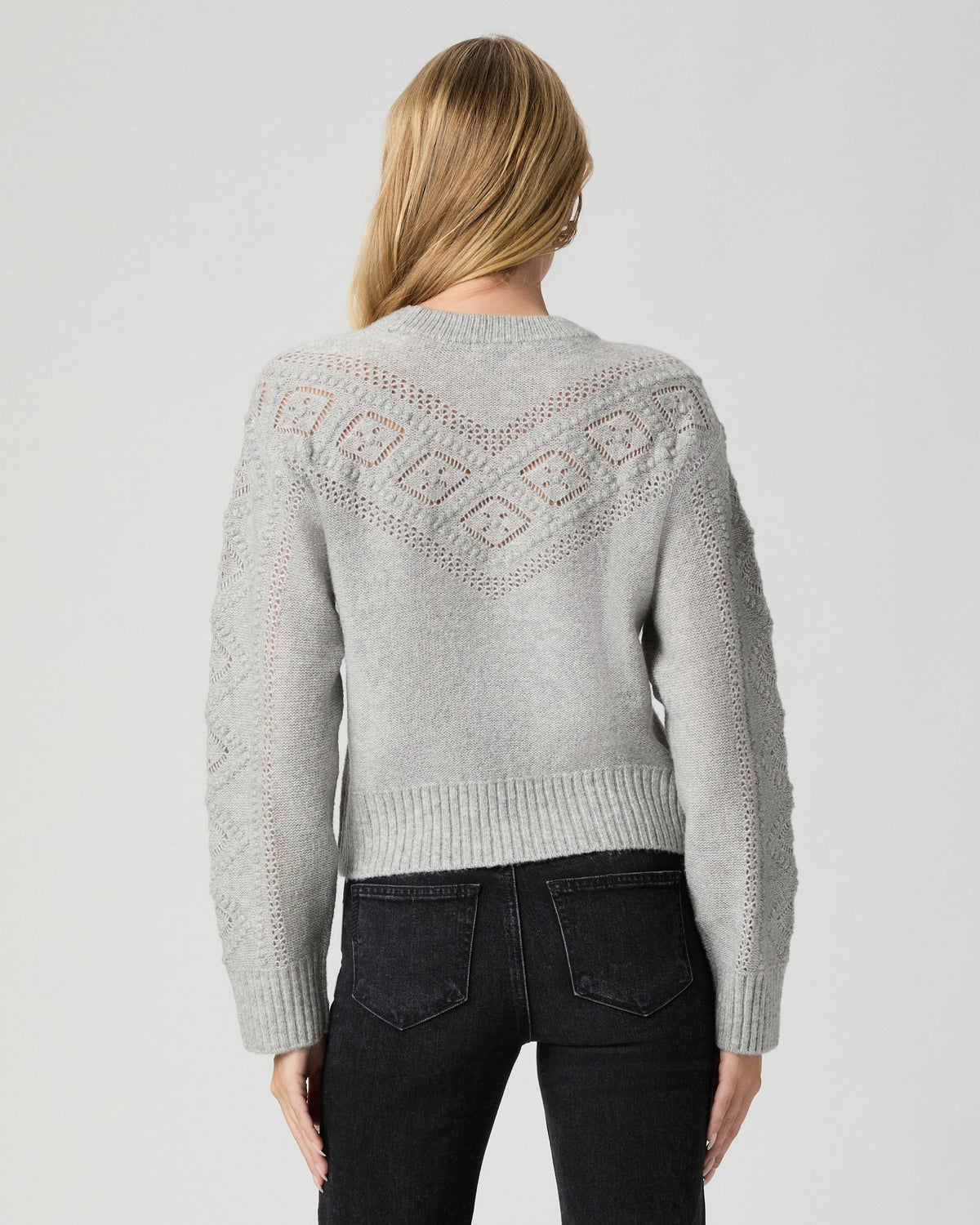 Back view of model wearing the Sutter Sweater in Light Heather Grey with black jeans