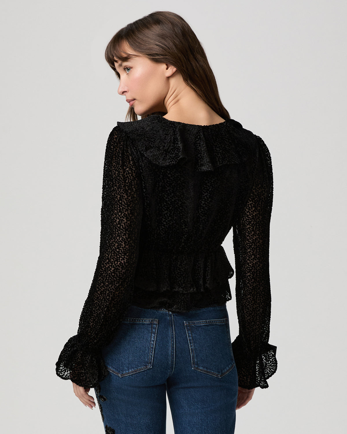 Back view of the black Aurelie Blouse showing sheer long sleeves with ruffled cuffs