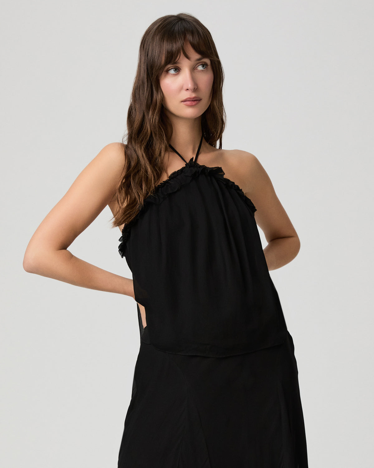 Close-up of the Noor Top in black viscose with a halter neckline and ruffled trim, styled with a matching black skirt