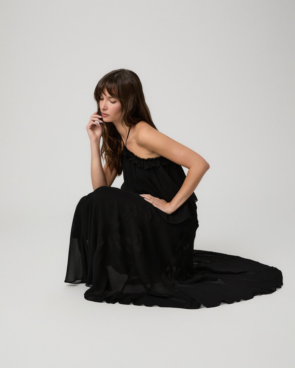 Model seated on the floor wearing the black Noor Top with a matching black maxi skirt
