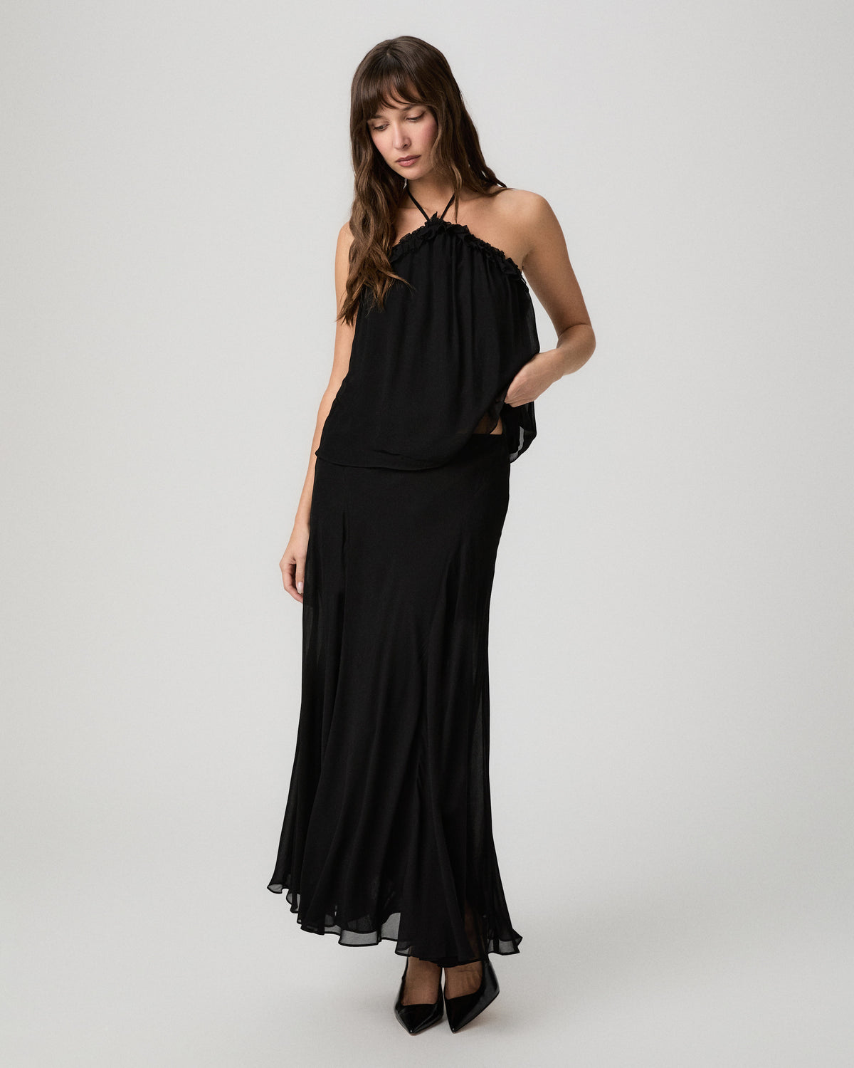 Full-length view of the black Noor halter top paired with a matching black maxi skirt and black heels