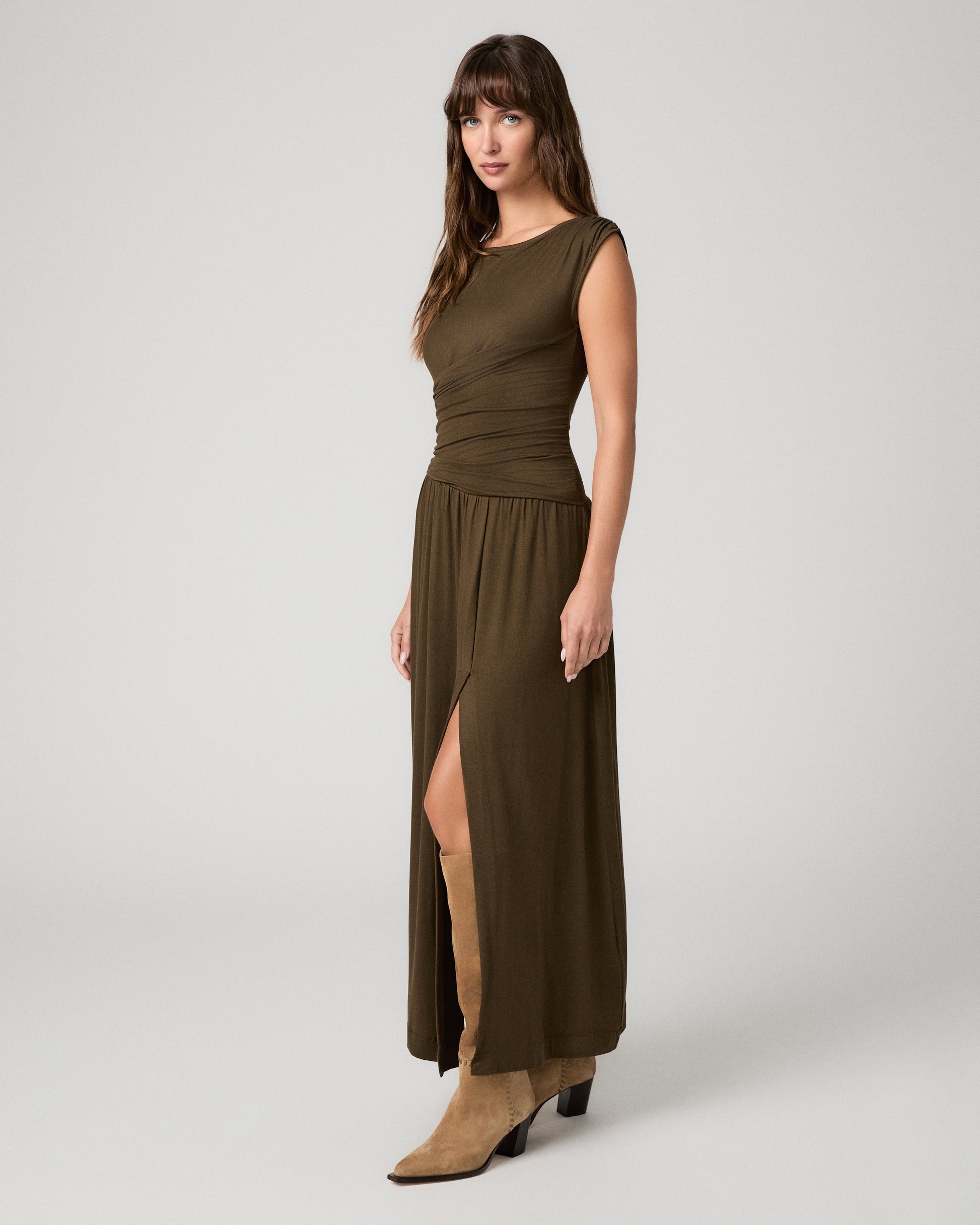 Women wearing a dark green maxi dress paired with brown boots against a white background
