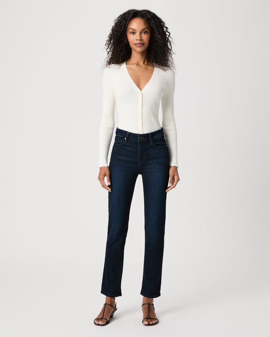 women wearing a white top paired with dark blue jeans and black sandals against a white background 