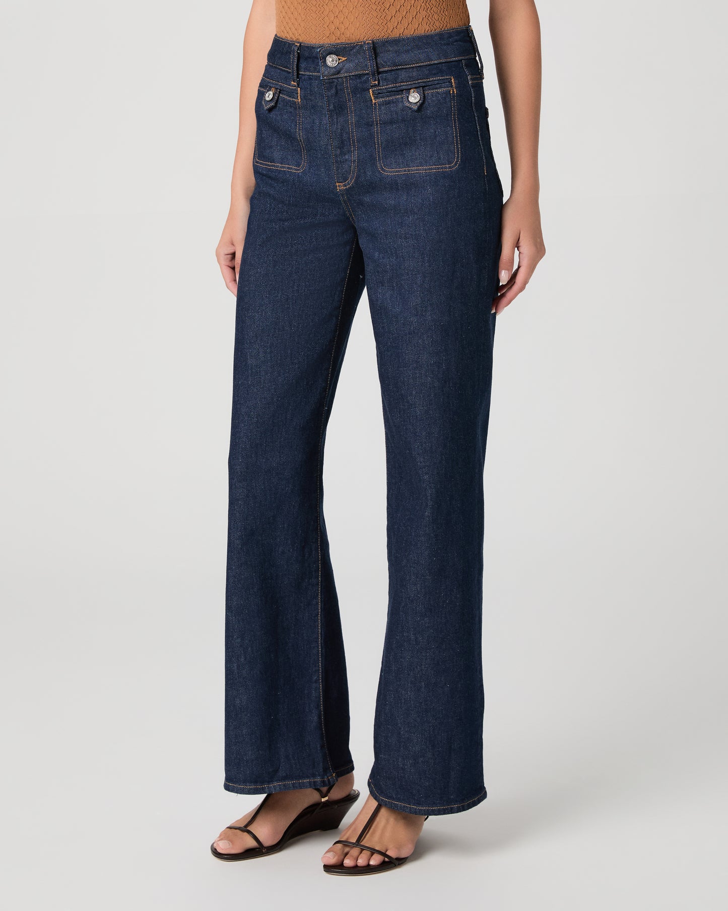Woman wearing a brown top and blue jeans on a white background