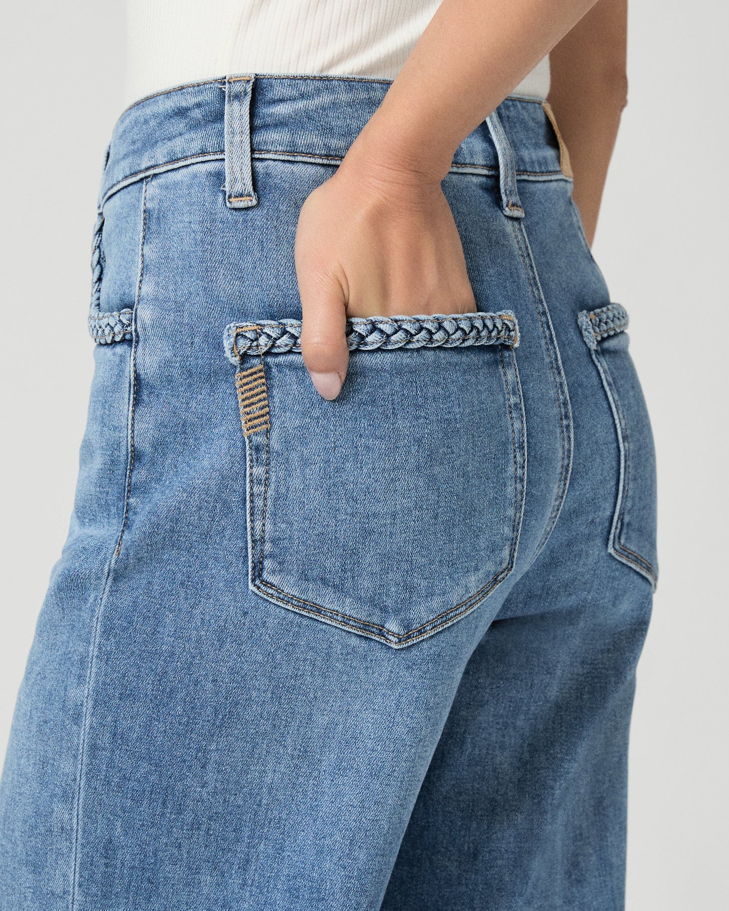 Woman wearing a white sleeveless top and blue jeans on a white background