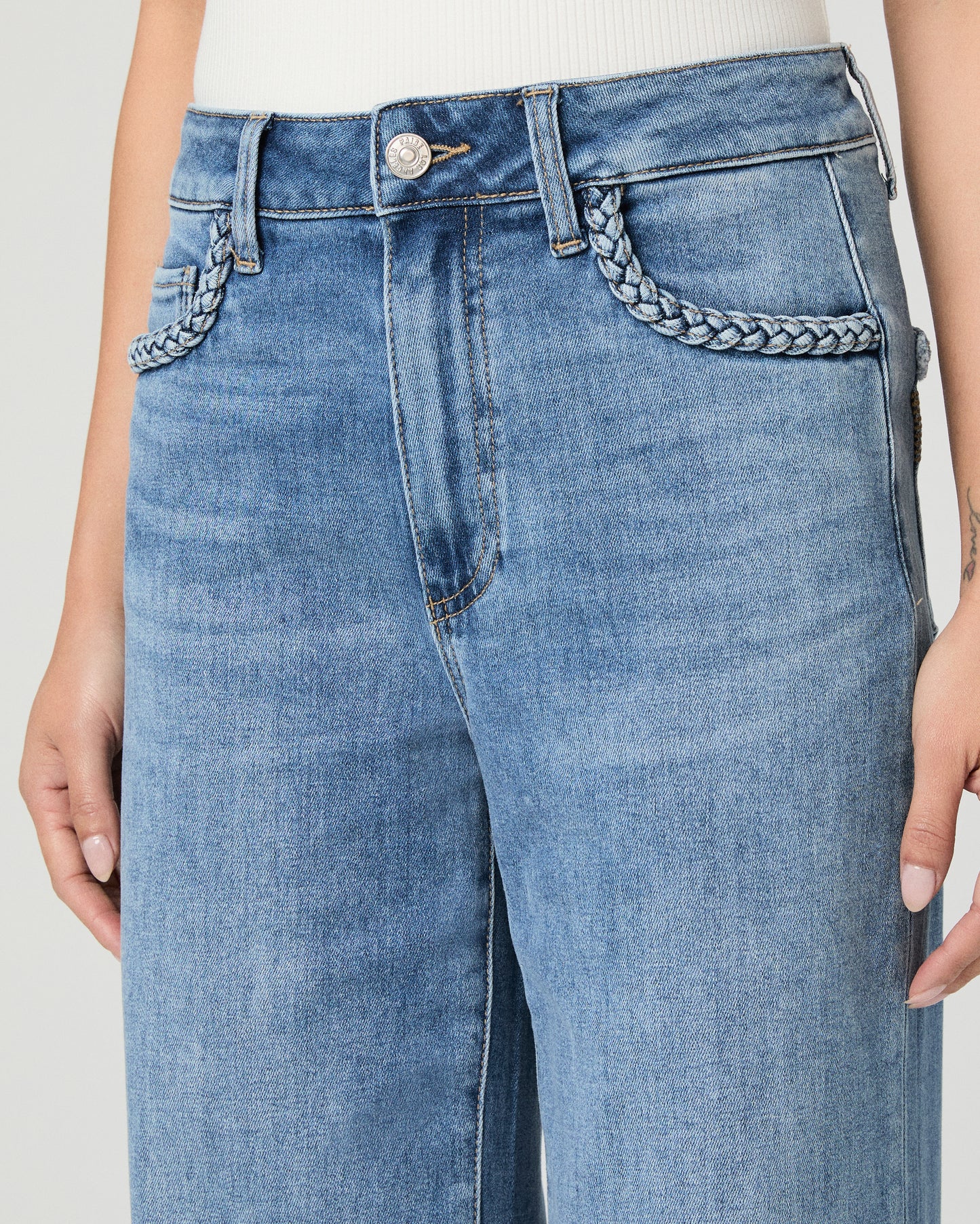 Woman wearing a white sleeveless top and blue jeans on a white background