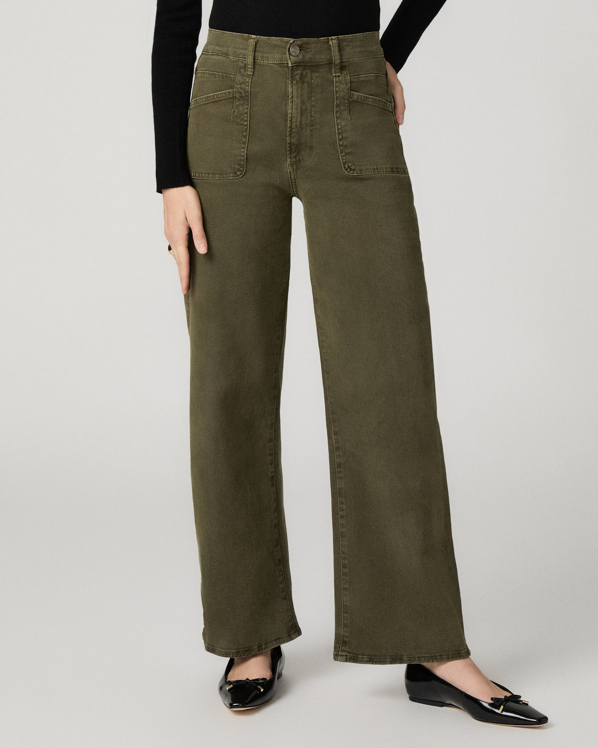 Close-up front view of the olive green Arellia Skimmer Barrel Leg Jean, showing the patch pocket detail and barrel-leg shape, paired with black flats.