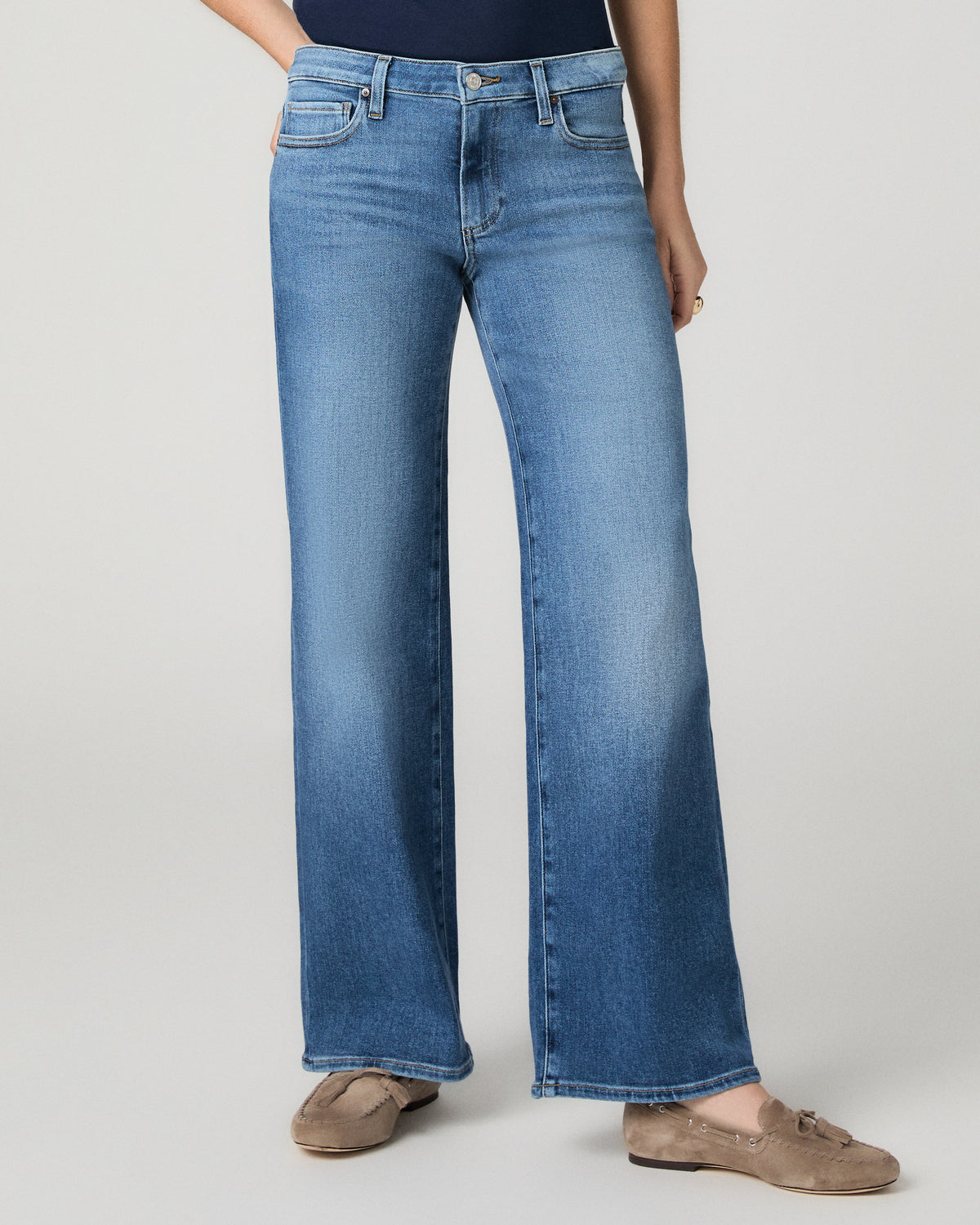Women wearing a blue tee paired with blue jeans standing against a white background