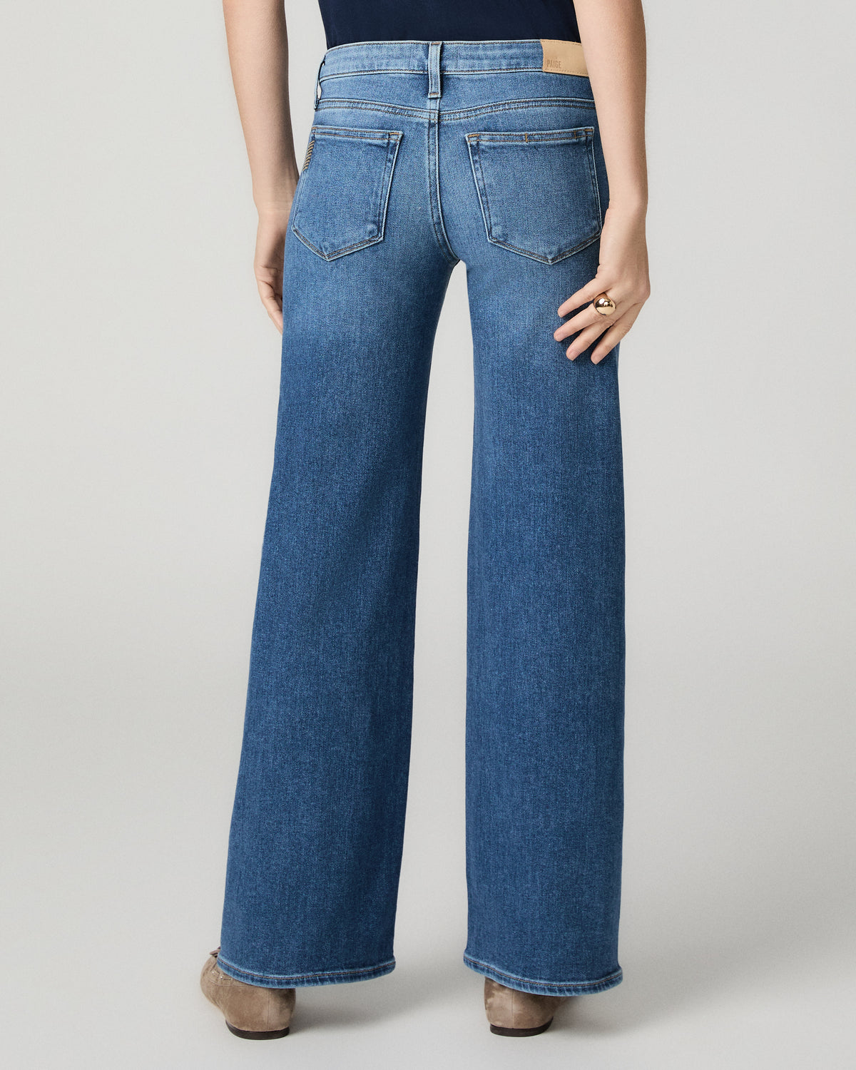 Women wearing a blue tee paired with blue jeans standing against a white background
