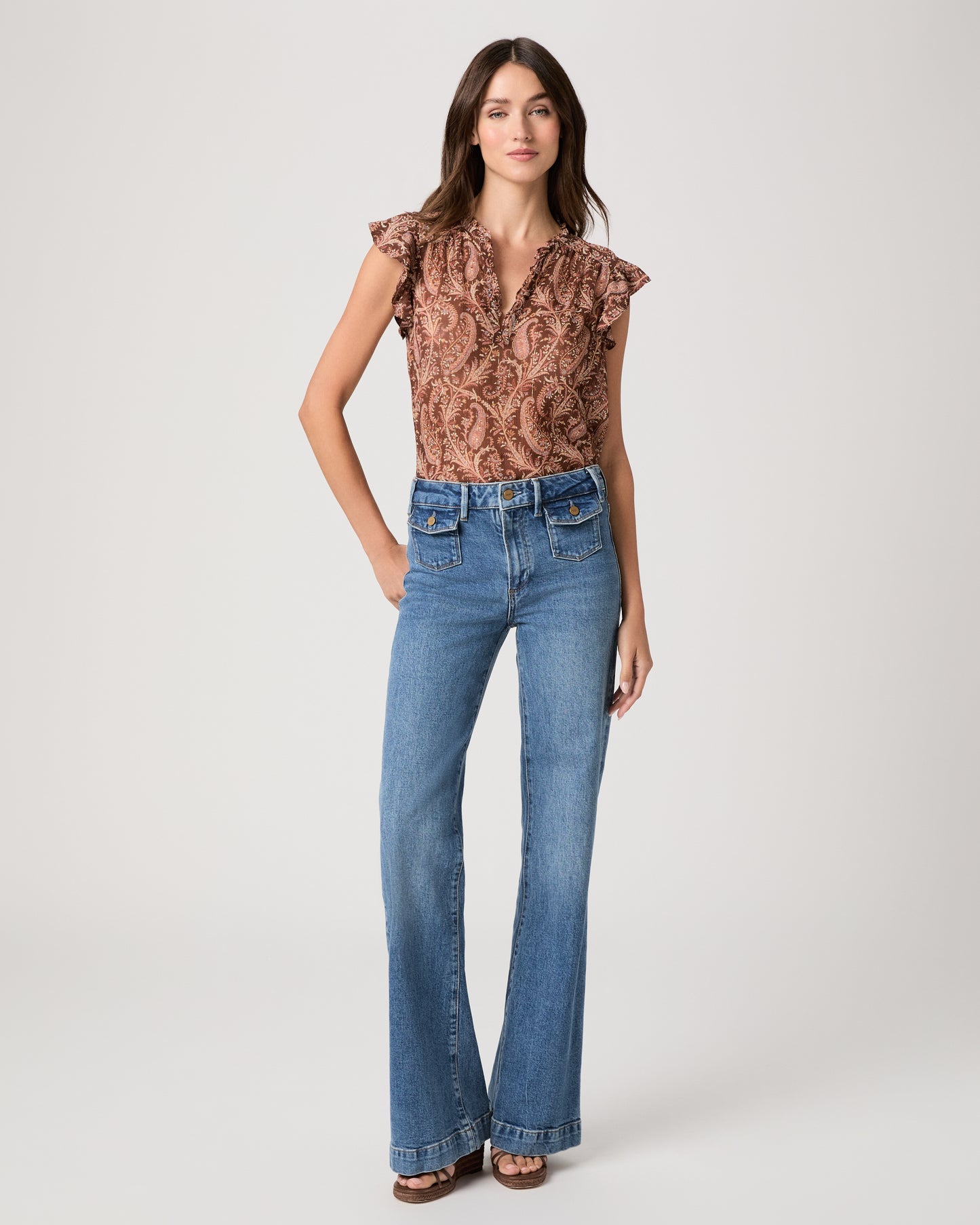Model wearing a printed brown short sleeve top paired with medium wash denim jeans and heeled brown sandals