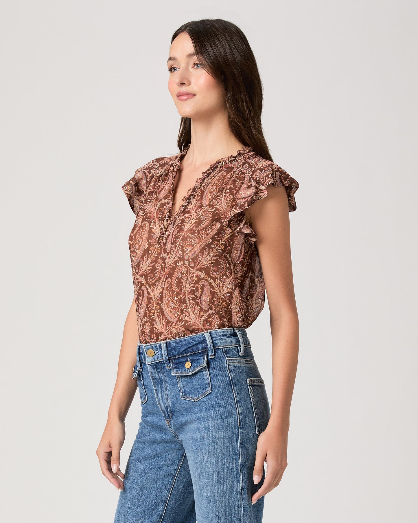 Model wearing a printed brown short sleeve top paired with medium wash denim jeans
