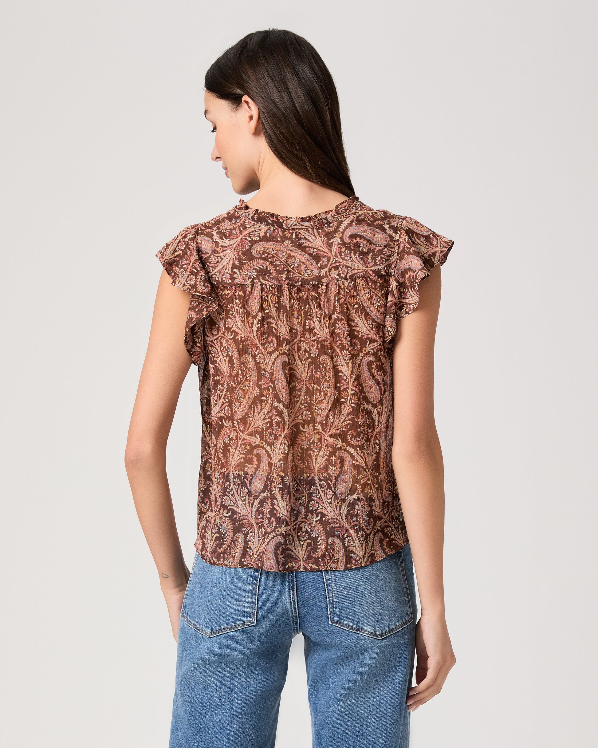 Model wearing a printed brown short sleeve top paired with medium wash denim jeans