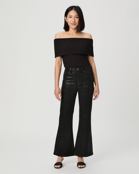 A woman modeling a black off-the-shoulder crop top and black wide-leg flare jeans against a light gray studio background.