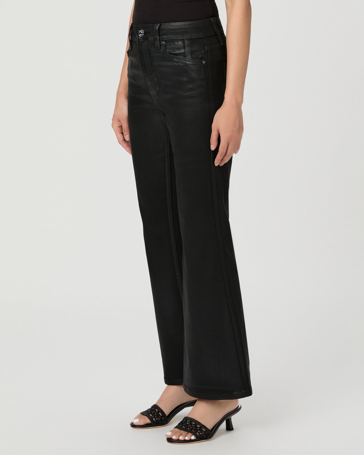 A woman modeling a black off-the-shoulder crop top and black wide-leg flare jeans against a light gray studio background.