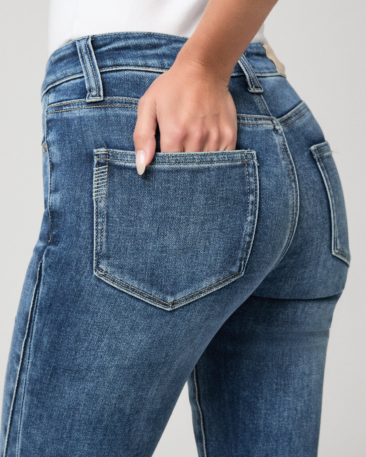 Woman wearing white top and blue pants against a white background