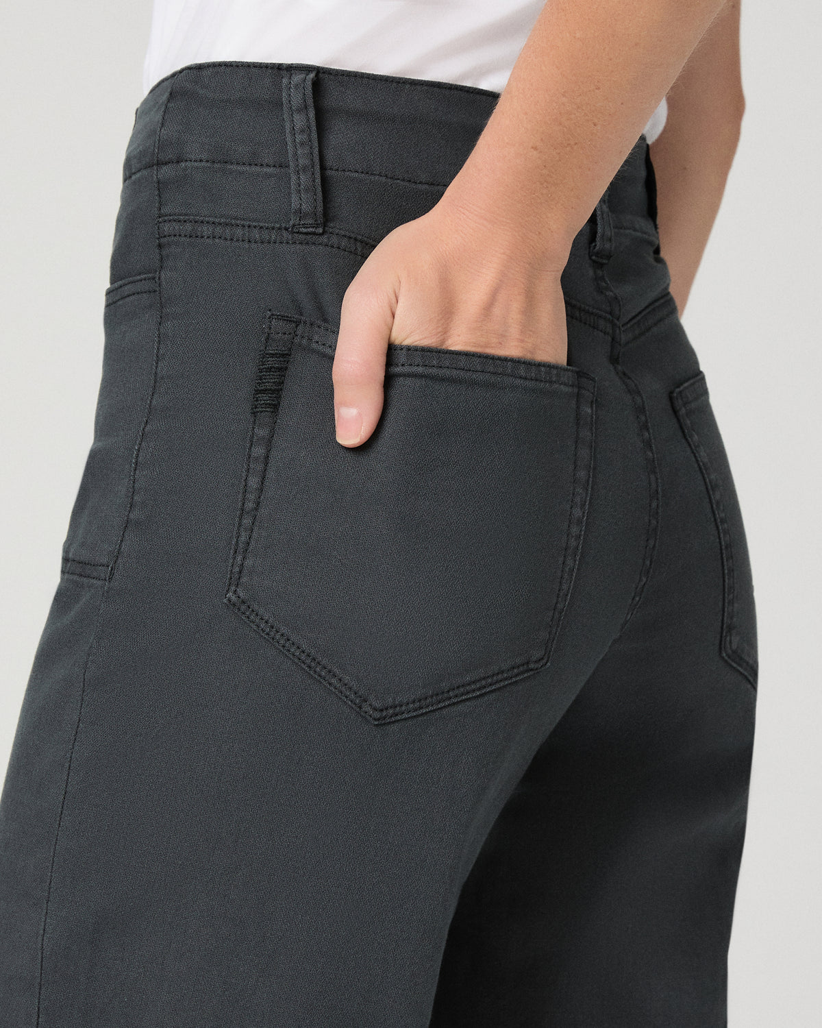 Women wearing a white tee and grey pants paired with brown flats against a white background