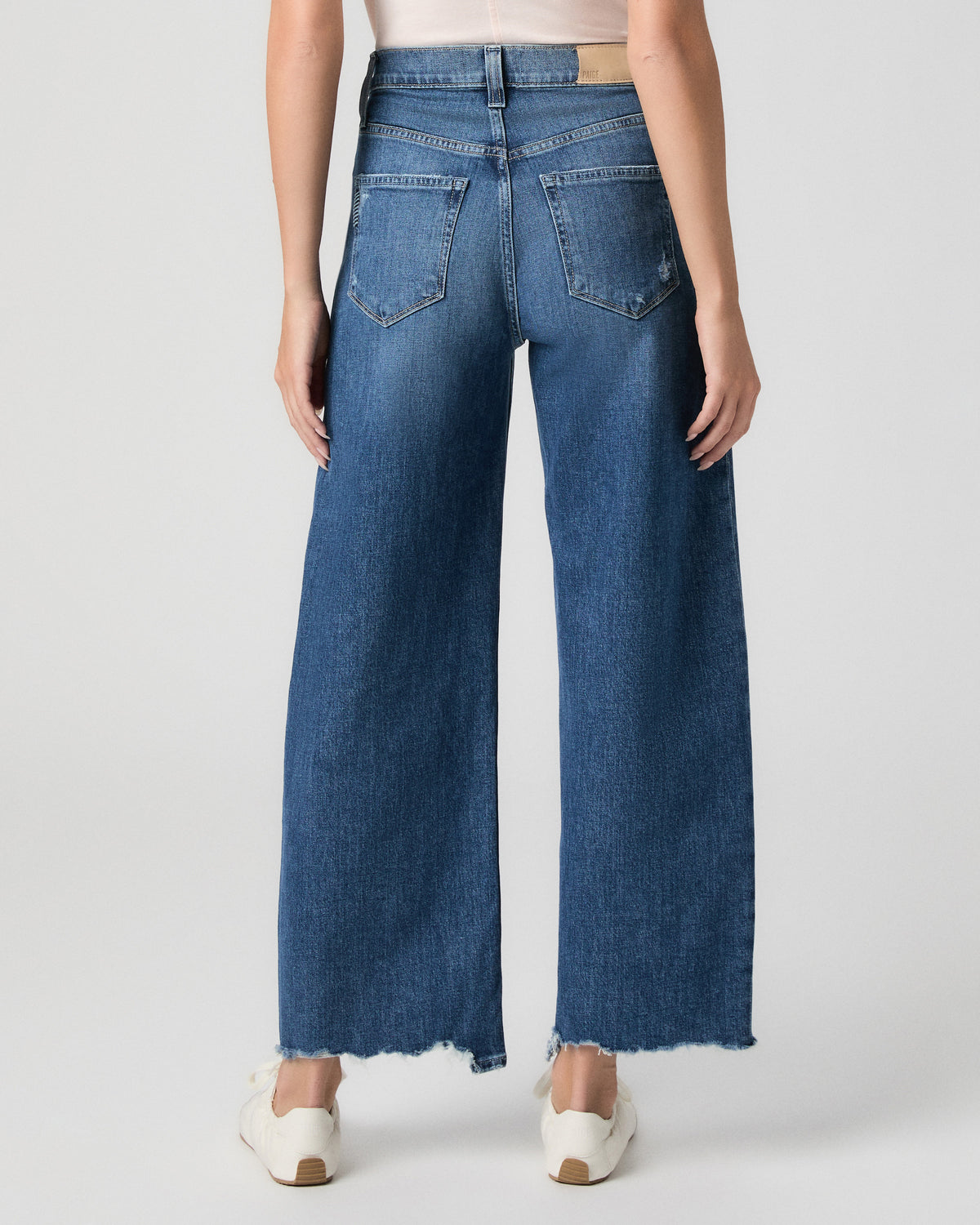 Back view from the waist down of the Arellia Ankle Barrel Leg Jean in Stoneview medium wash, worn with white sneakers