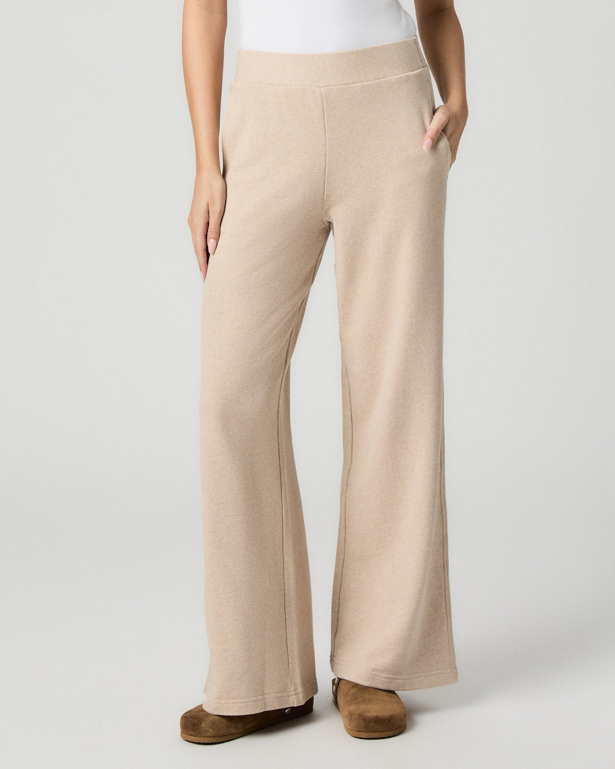 Front view from the waist down of the Whistler Pant in Heathered Oatmeal, worn with a white top and brown suede clogs