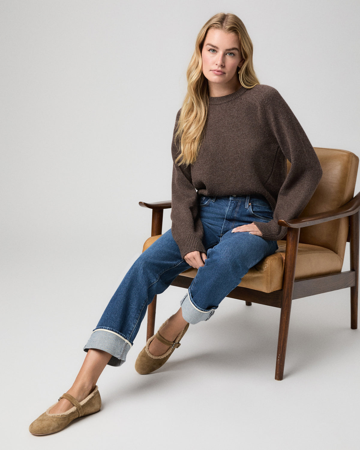 Stevie Straight Jean in Soundcheck dark wash; model sits in a leather armchair in a brown sweater and tan suede flats