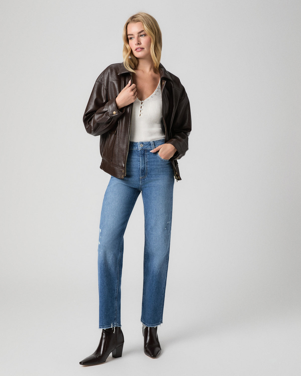 Stevie Ankle Straight Jean in Frittata Dest light-medium wash; model stands with a hand in her pocket, in a brown leather jacket, white henley and black ankle boots