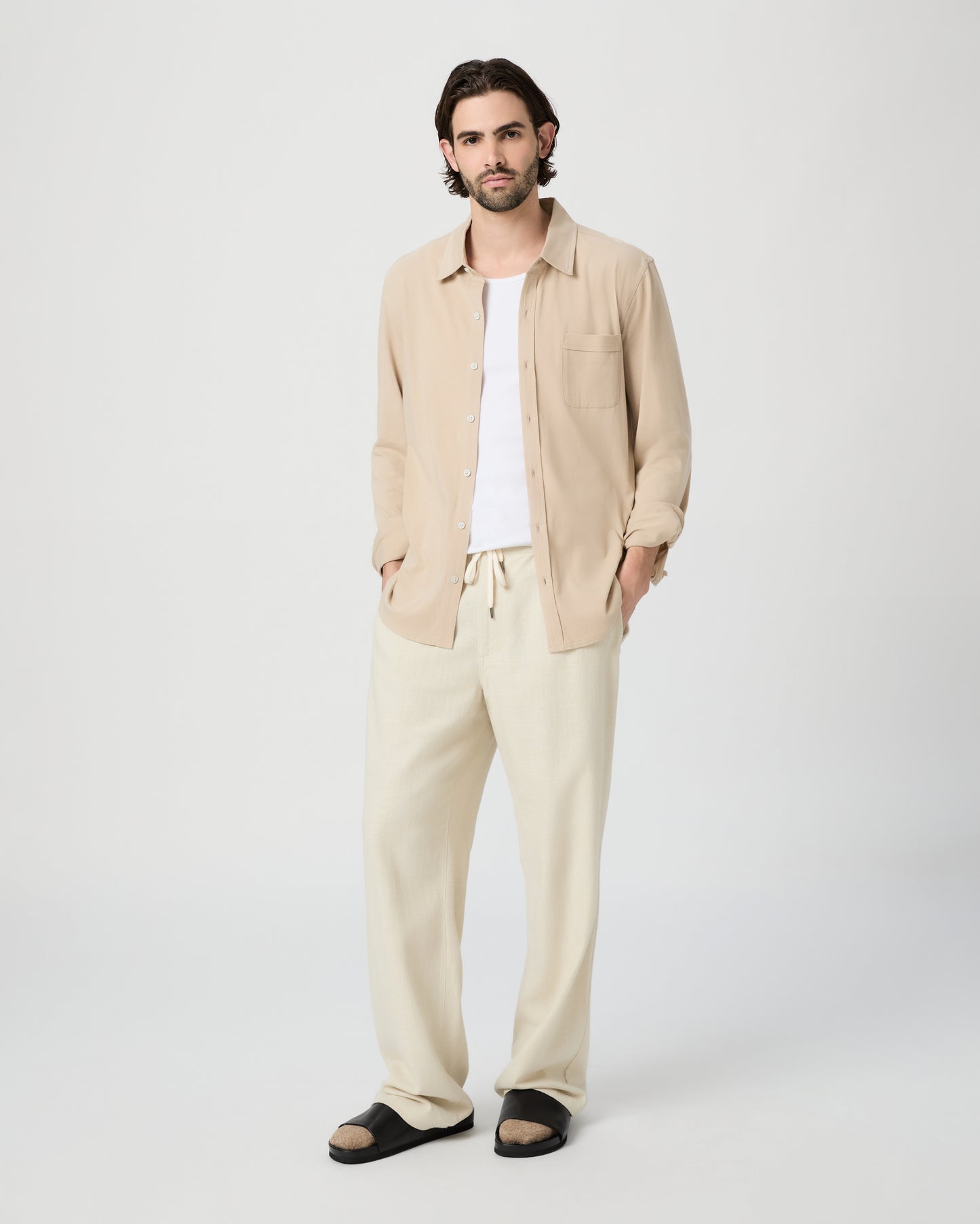 Man wearing a beige shirt and pants on a white background